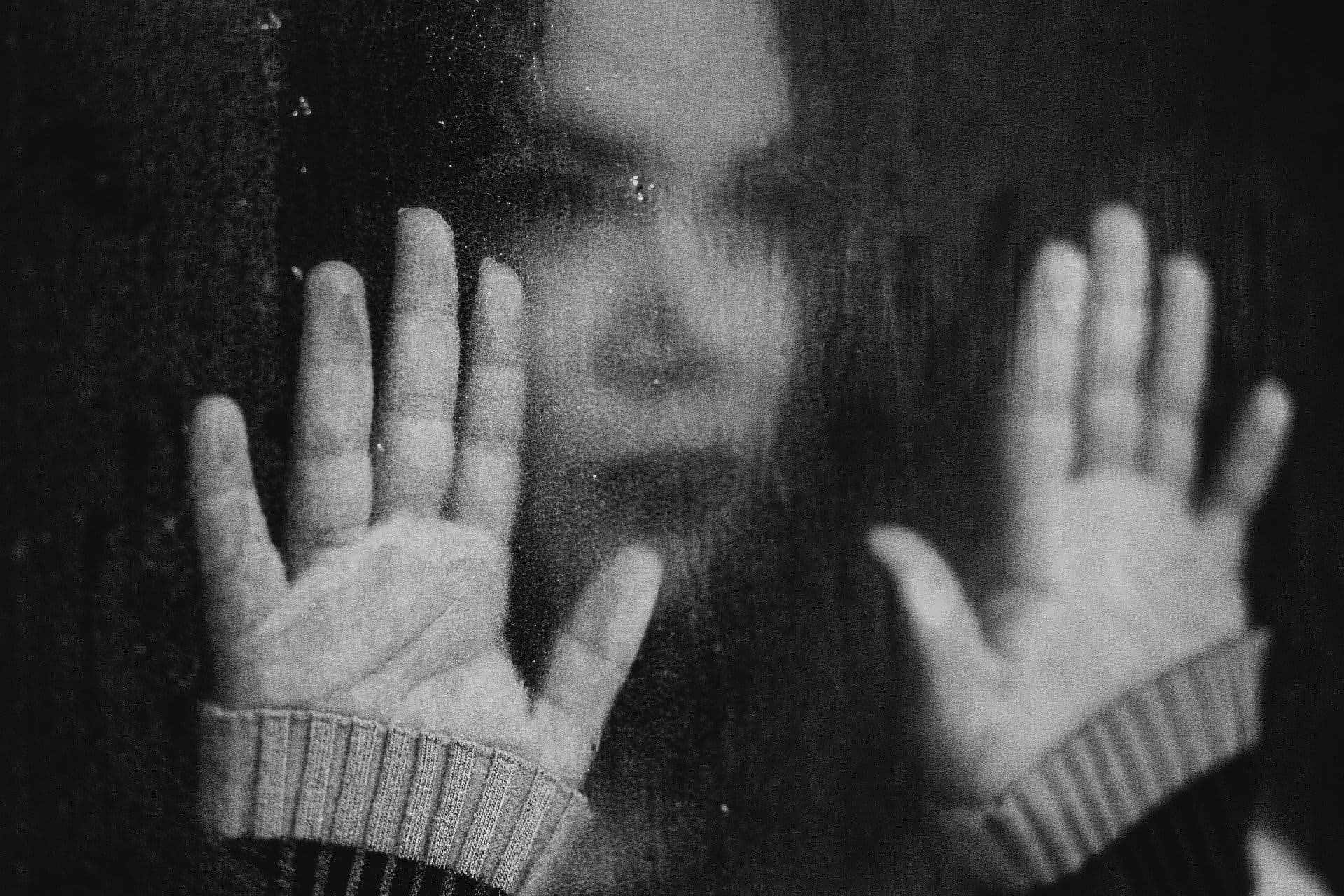 Femme mains contre vitre mouillée par la pluie